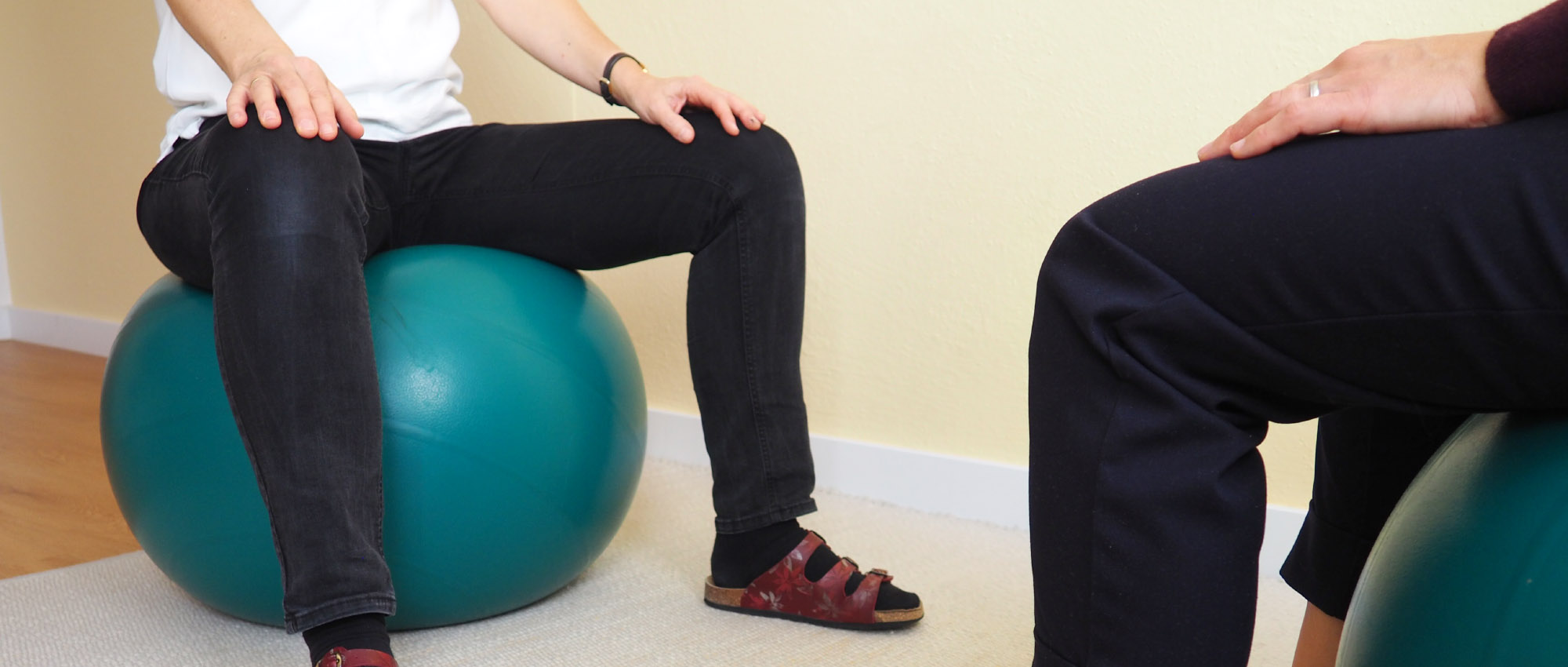 Zwei Personen sitzen sich auf einem Pezzi Ball gegenüber